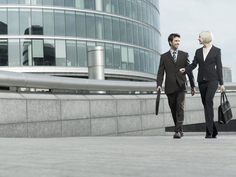 man and woman walking beside office building